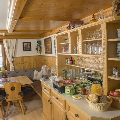 Der Essbereich des Bauernhofs mit Frühstücksbuffet, Holztisch und Eckbank.
