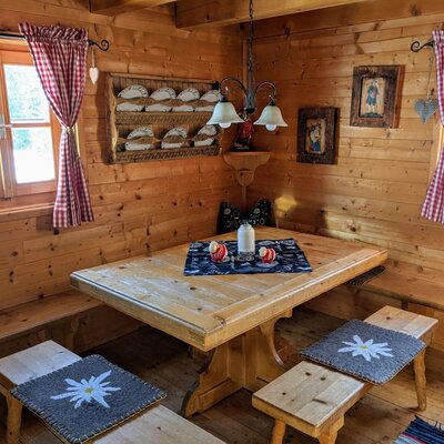 Essbereich mit Holztisch und Sitzbänken in der Wohnkochstube des Hofes.