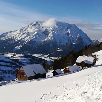 Der Hof und umliegende Gebäude in einer verschneiten Berglandschaft mit Talblick.