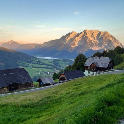 Der Hof liegt inmitten einer grünen Berglandschaft mit Ausblick auf die umliegenden Berge und das Tal.